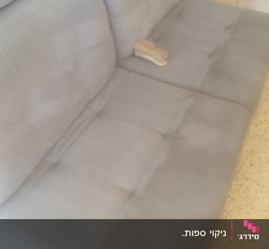 ספה אפורה עם מברשת ניקוי על המושב